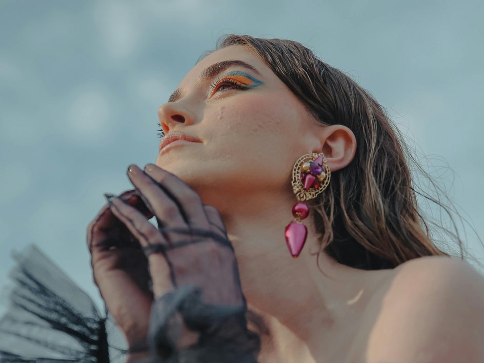 before: female portrait gazing at sky with colorful earrings and accessories
